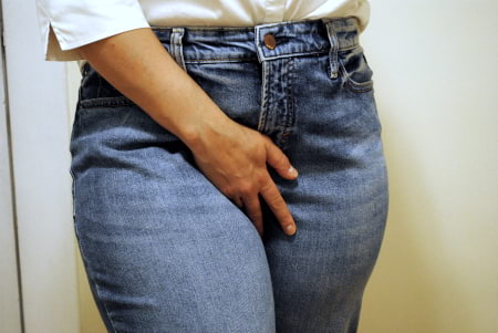 A person holding their crotch as if they have to pee, an act that can be arousing to someone engaging in wetting fetish