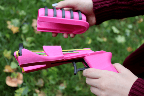 A woman holding the slide of The Snapper 2.0 in one hand, and the rest of the gun in the other hand, showing what it looks like when it's loaded. 